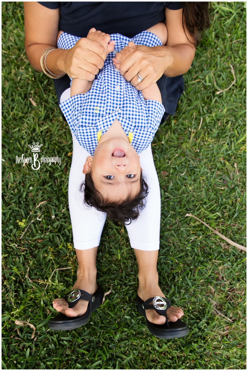 laughing baby boy lying on mom's legs in the grass