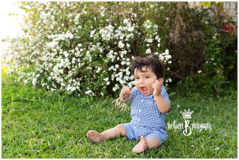 excited baby boy sitting in grass playing with mom's bracelets