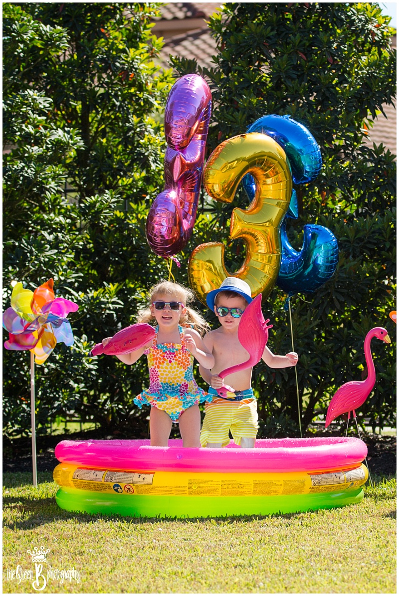 Boy girl twins playing in pool with pink flamingos for third birthday