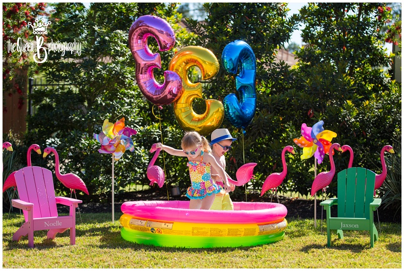 super bright fun birthday photo shoot with twins in inflatable pool with pinwheels and flamingos