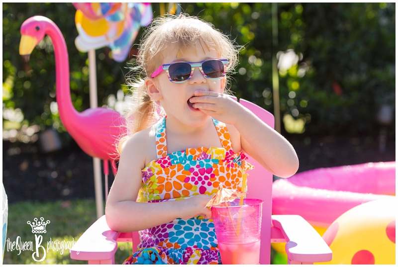 little girl in sunglasses and bathing suit enjoying cool umbrella drink with pink flamingo