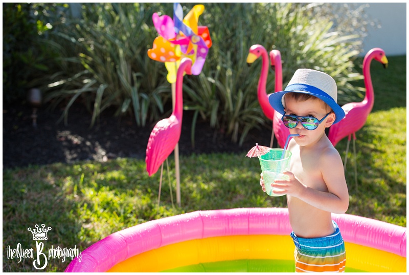 toddler boy in bright colored pool party enjoying cool umbrella drink