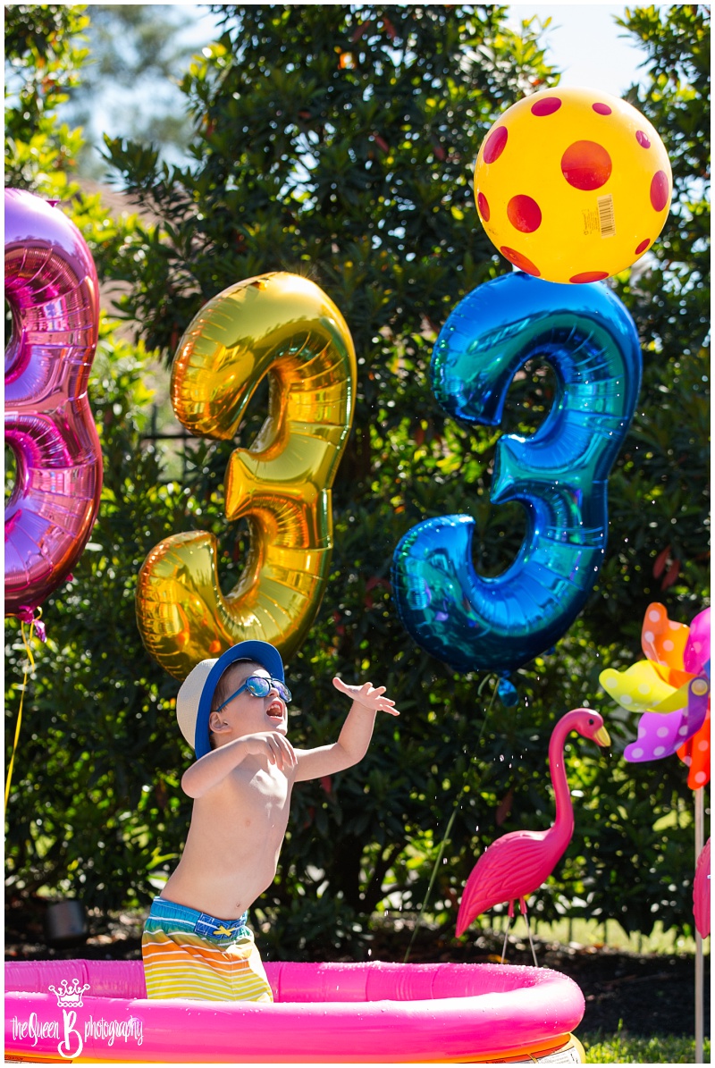 toddler boy playing with beach ball at bright colored pool party