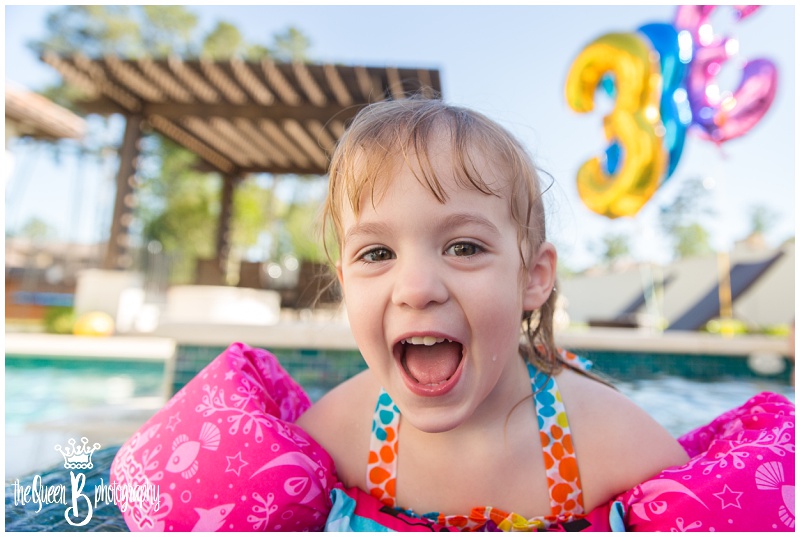 happy three year old girl in floaties at the pool