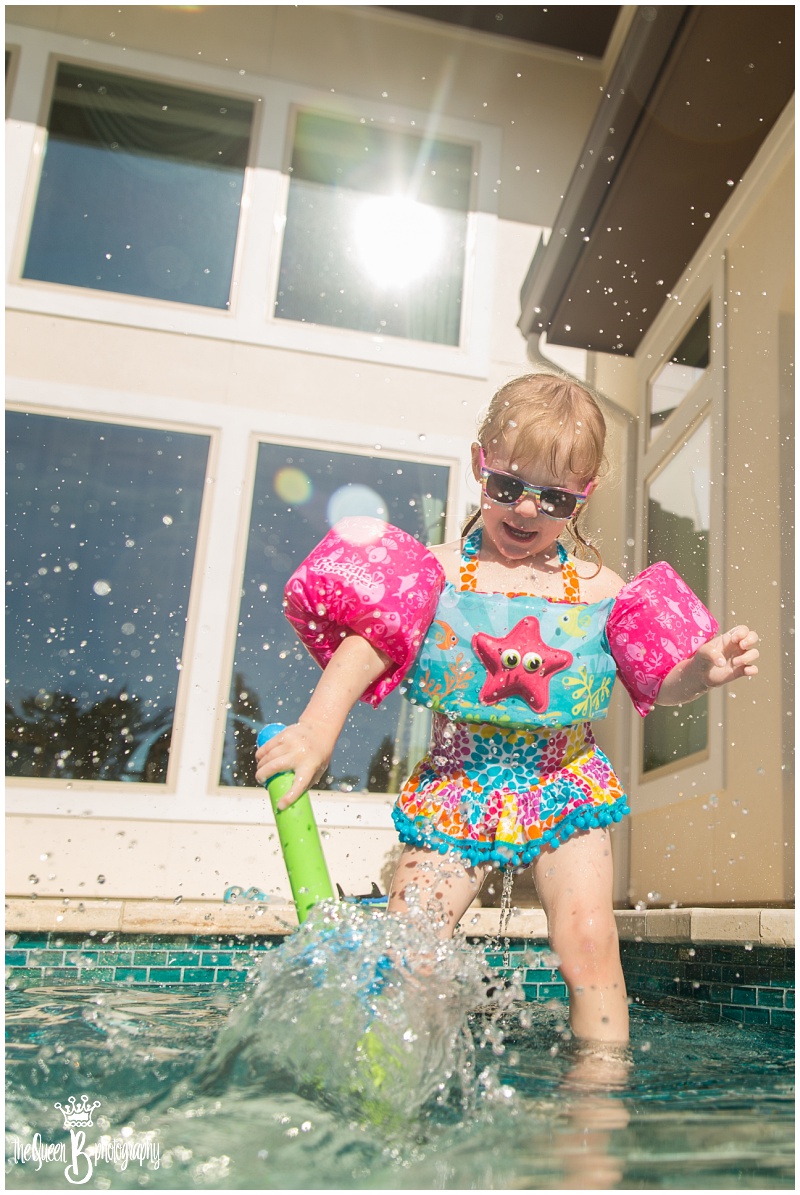 toddler girl splashing in swimming pool 