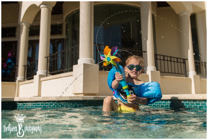 toddler boy with pinwheel toy splashing in pool 