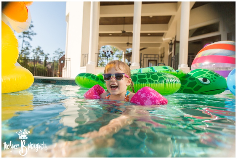 toddler girl in pink floaties and sunglasses in the swimming pool