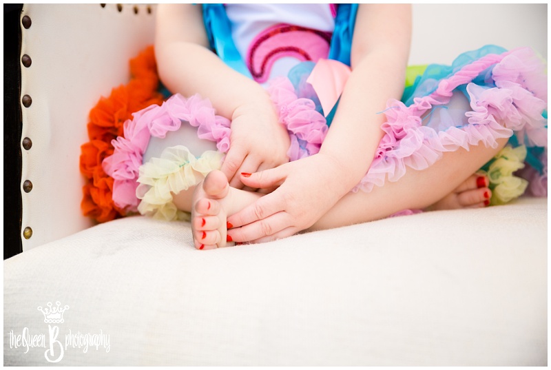 toddler girl painted toes and fingers with rainbow colored tutu