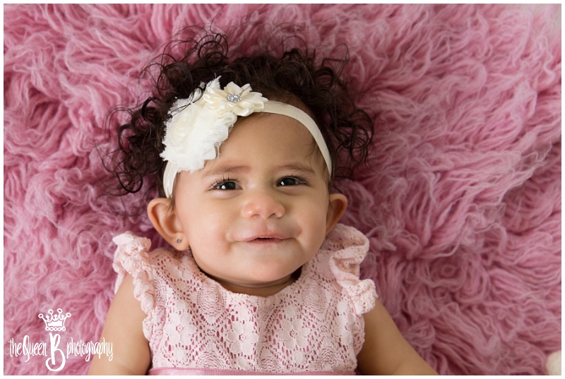 smiling baby girl on pink furry rug in Houston Baby Photographer studio