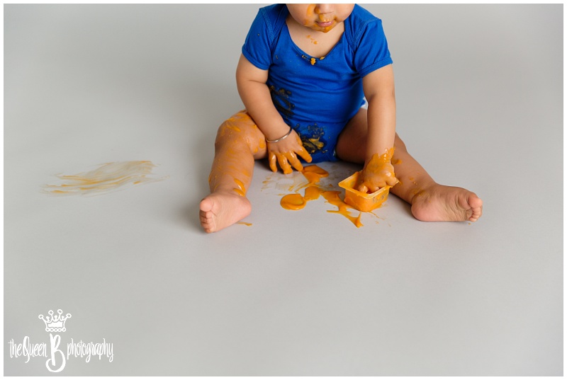 1 year old in blue making a huge mess with orange baby food