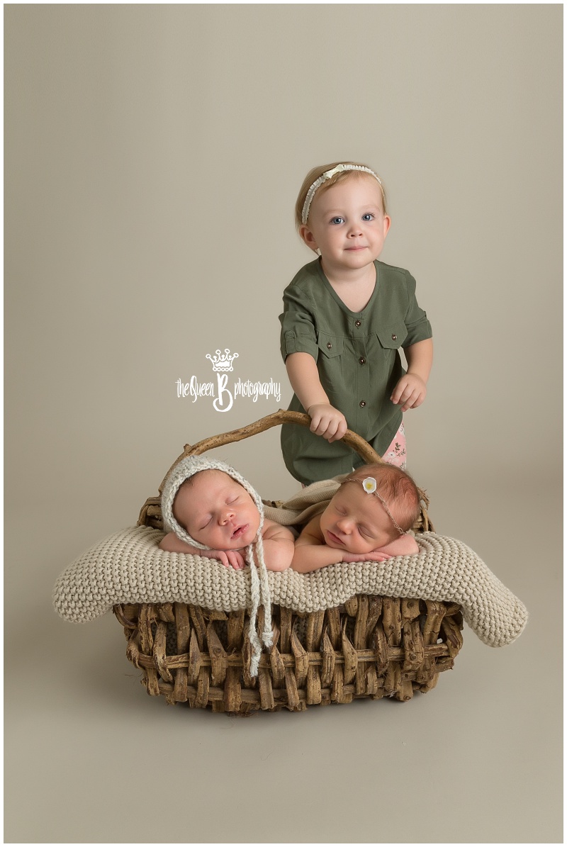 toddler big sister posing with sleeping twins in basket
