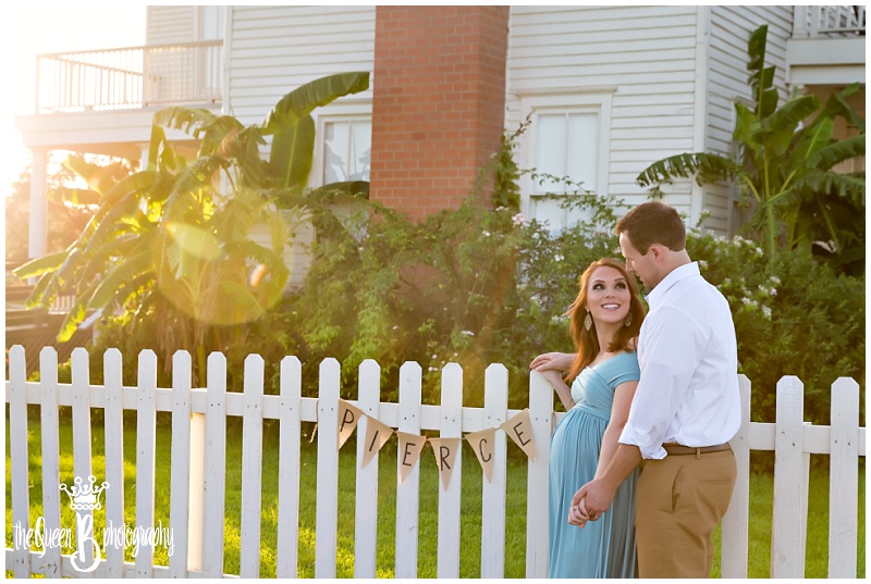 Stunning Sunset Maternity Portraits of couple by white picket fence