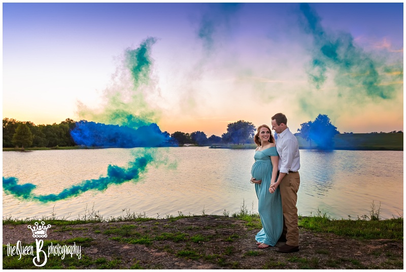 Sunset gender reveal portrait at the lake with blue smoke bomb