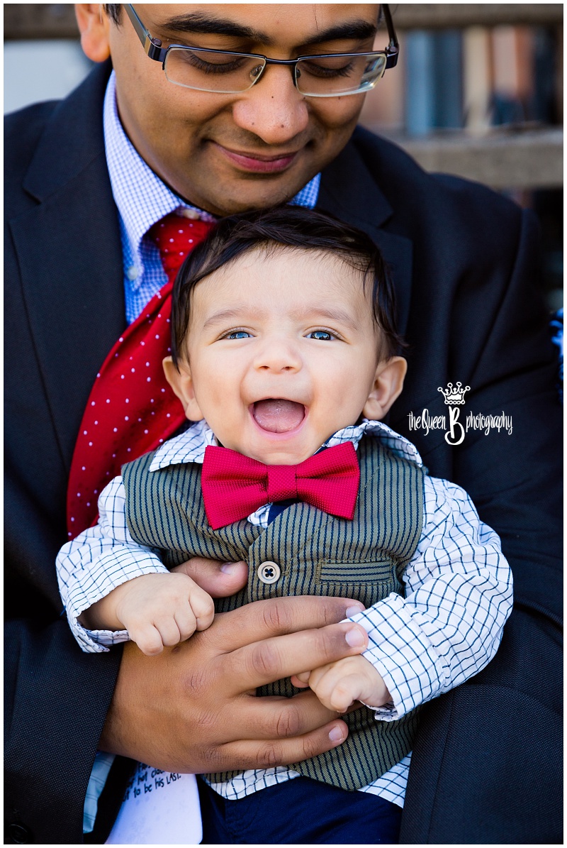 adorable baby boy with red bow tie sitting in father's lap