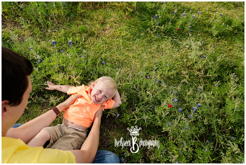 sweet toddler boy playing with father in texas wildflowers