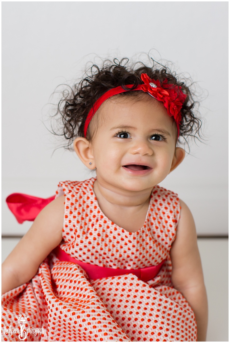 big brown eyed curly haired baby girl in white studio