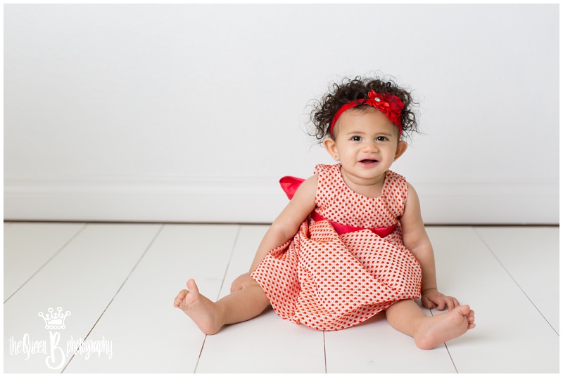 curly haired baby girl in red polka dot dress at Houston Baby Photography Studio