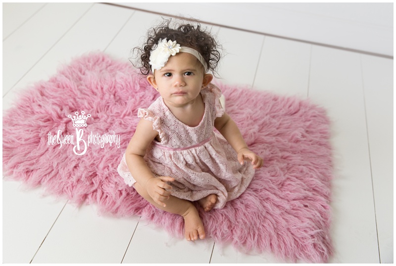 precious baby girl sitting on pink furry rug
