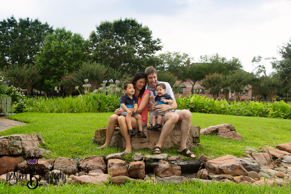 happy family of two boys sitting on rock in beautiful Houston park