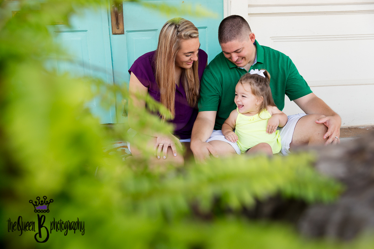 Houston Family Photographer documents laughing toddler and family against teal door