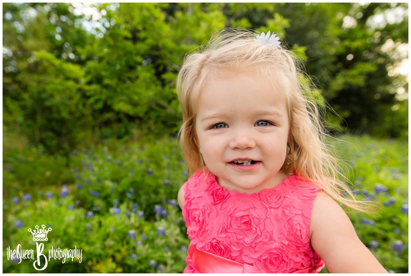 beautiful toddler girl in coral dress among texas bluebonnet flowers