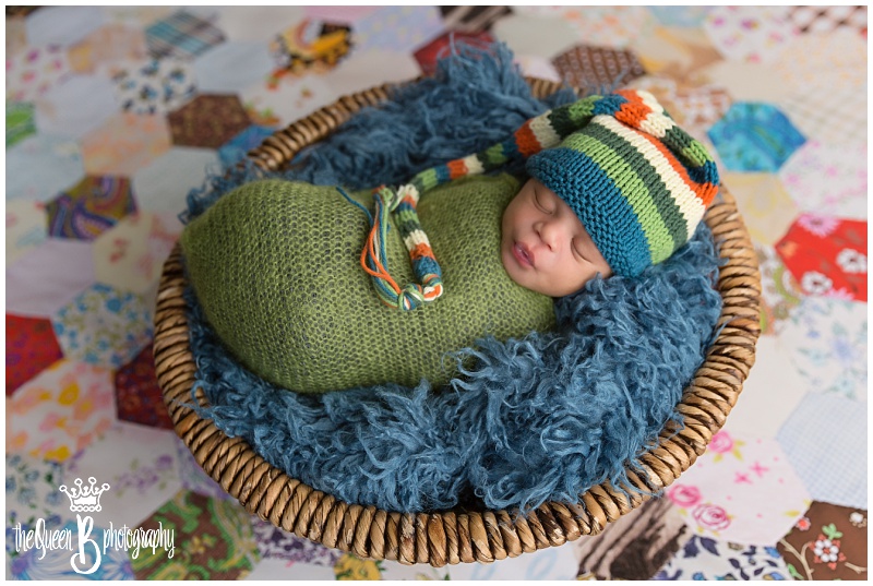 Newborn baby boy in basket on colorful patchwork quilt