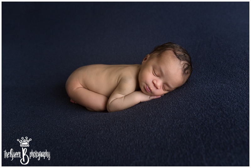 Curled up sleeping infant on dark blue background